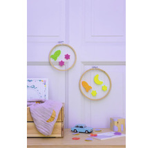 Dekorative Kinderzimmer Szene mit Stickrahmen, Raketen, Sternen, Halbmond, Spielzeugauto und Holzkiste auf einem Tisch vor einer Wand