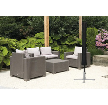 Gartenszene mit grauer Rattansitzgruppe und schwarzer Schutzhülle für Sonnenschirm
