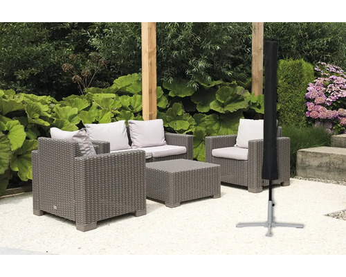 Gartenszene mit grauer Rattansitzgruppe und schwarzer Schutzhülle für Sonnenschirm