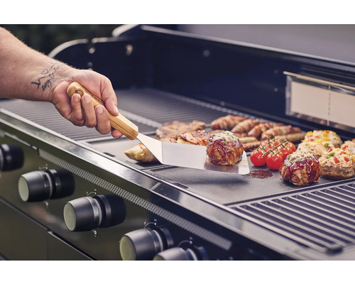 Gasgrill mit Grillgut und Grillbesteck im Einsatz