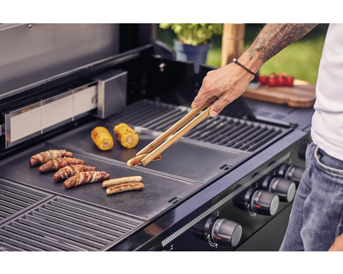 Mann grillt Würstchen und Maiskolben auf einem Grill