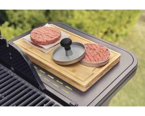 Burgerpresse mit Fleischpatties auf einem Schneidebrett