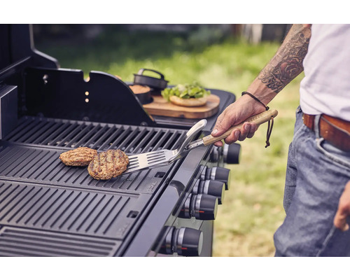 Person wendet Burger auf einem Grill mit einem Pfannenwender