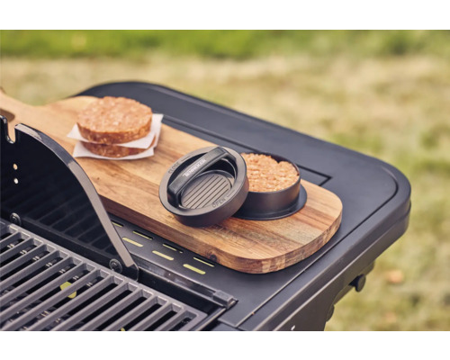 Burgerpresse mit zwei Fleisch-Burgern auf einem Grilltisch