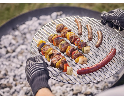 Grillrost mit Fleischspießen und Würstchen über Holzkohle