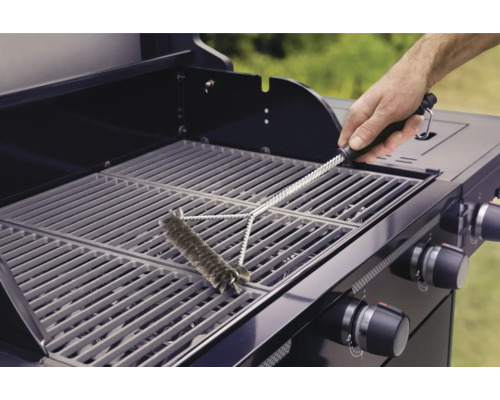 Eine Person reinigt mit einer Grillbürste einen Grillrost.