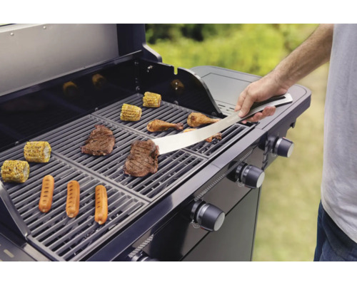 Person grillt Steaks, Würstchen, Mais und Hähnchen auf einem Gasgrill.