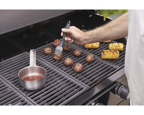 Fleischbällchen und Maiskolben werden auf einem Grill zubereitet.