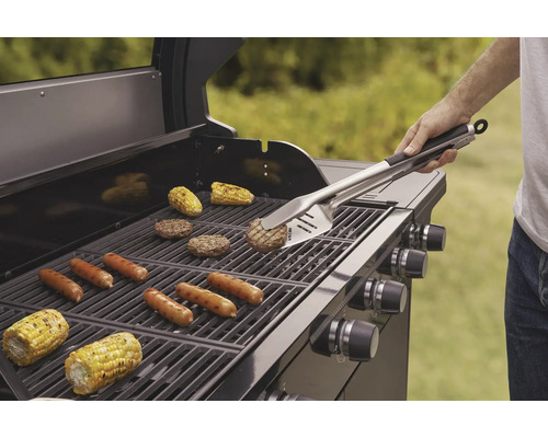 Grill mit Grillgut wie Würstchen, Burger und Maiskolben, bedient mit Grillbesteck