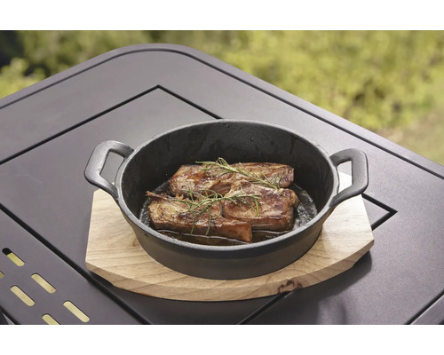 Gegrilltes Fleisch mit Rosmarin in einer schwarzen gusseisernen Pfanne auf einem Holztisch