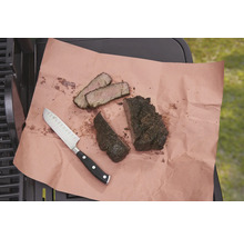 Auf einem Stück Papier liegen ein Messer und aufgeschnittenes Fleisch.