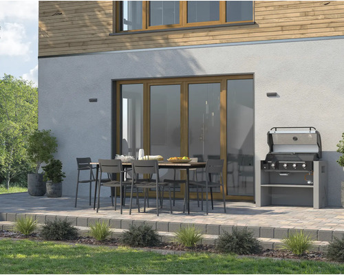 Außenbereich mit Gartengrill, Esstisch und Stühlen vor einem Haus