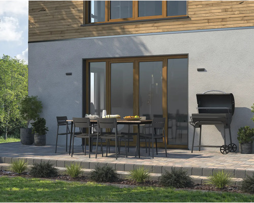 Außenbereich mit Gartentisch, Stühlen und Grill auf einer gepflasterten Terrasse