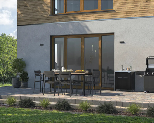 Terrasse mit Esstisch, Stühlen, Spüle und Grill vor einem Haus.