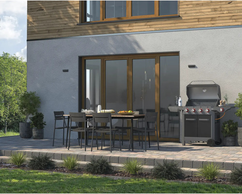 Terrasse mit Gartengrill, Tisch und Stühlen vor Hauswand