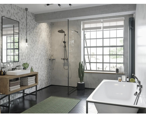 Badezimmer mit Dusche, Badewanne, Waschbecken, Spiegel und Fliesen in geometrischem Muster.