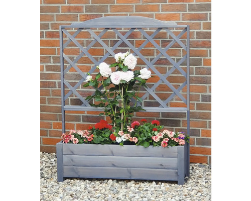 Blumenkasten mit Rankgitter vor einer Ziegelwand