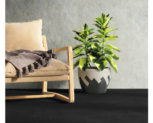Innenraumszene mit Sessel, Kissen, Zimmerpflanze und dunklem Bodenbelag
