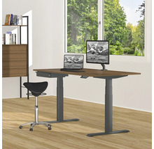 Höhenverstellbarer Schreibtisch mit Laptop, Monitor und Bürostuhl in einem hellen Raum.
