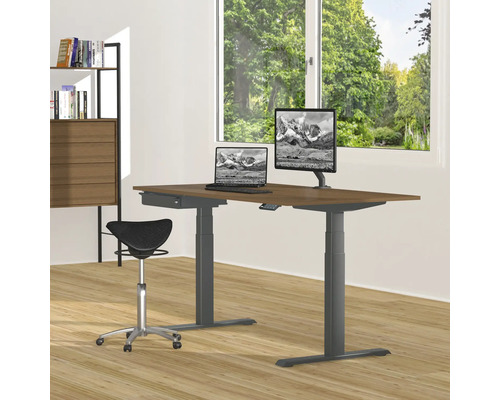 Höhenverstellbarer Schreibtisch mit Laptop, Monitor und Bürostuhl in einem hellen Raum.
