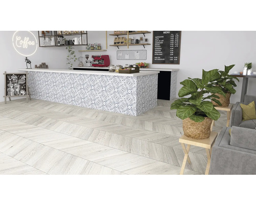 Innenaufnahme eines Cafés mit Holzboden in Fischgrätmuster, einer Theke mit gemusterten Fliesen und Zimmerpflanzen