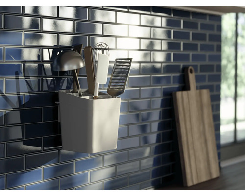 Küchenszene mit dunkelblauen Fliesen, Küchenutensilienhalter und Schneidebrett