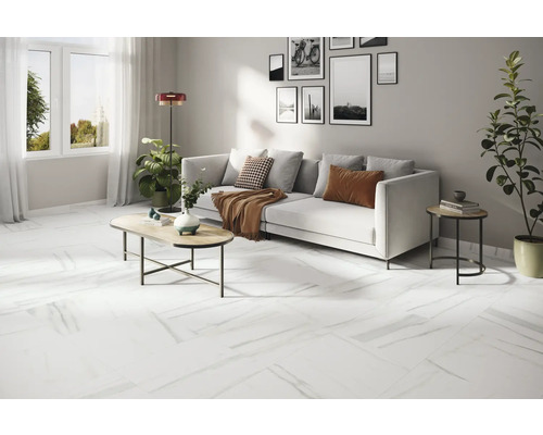 Heller Wohnraum mit weißem Sofa, Couchtisch und weißem Bodenbelag in Marmoroptik.