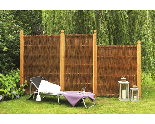 Gartenszene mit Sichtschutz aus Weide und Holzpfosten, Liegestuhl und Laternen