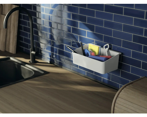 Wandmontierter Organizer mit Büroartikeln an einer blauen gefliesten Wand über einer Küchentheke