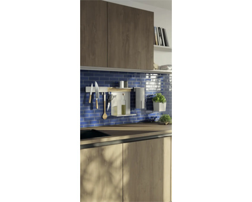 Küchenszene mit Küchenutensilien an einer Relingstange und Kräutern in Töpfen