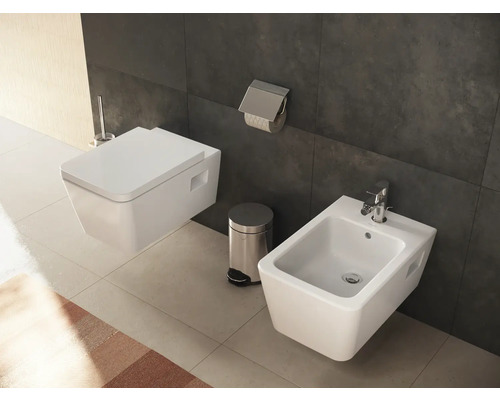 Wandhängendes WC und Bidet in einem Badezimmer mit Toilettenpapierhalter und Mülleimer