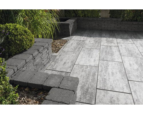 Terrasse mit Pflastersteinen und Steinmauer im Garten