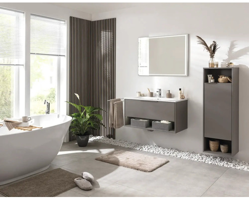 Badezimmer mit Badewanne, Waschtisch, Spiegel und Schrank für Badezimmerutensilien.