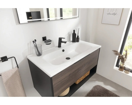 Waschtisch mit Unterschrank, Armatur, Spiegel und Badaccessoires in einem Badezimmer