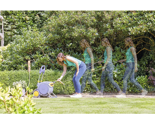 Frau benutzt eine Schlauchbox im Garten, um Pflanzen zu bewässern.