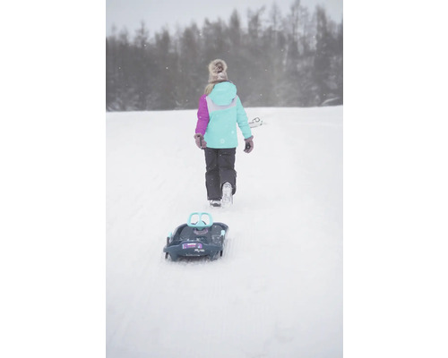 Ein Mädchen zieht einen Schlitten durch den Schnee.