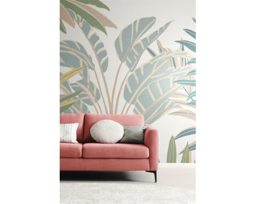 Wohnzimmer mit pinkfarbenem Sofa vor einer Wand mit Pflanzenmuster