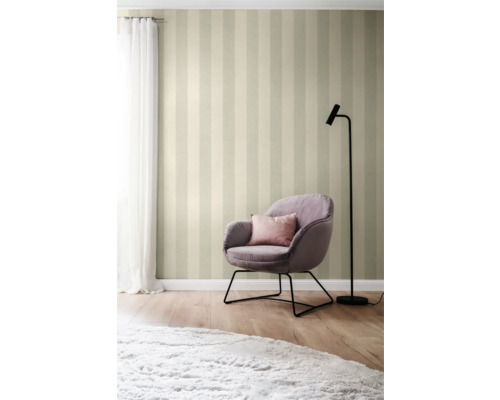 Gestriifte Tapete mit Sessel, Kissen, Lampe und Teppich in einem hellen Raum.