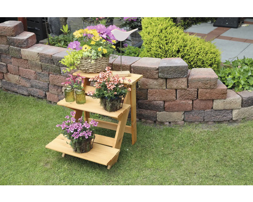 Dekorative Holztreppe mit Blumen auf Rasen vor Steinmauer