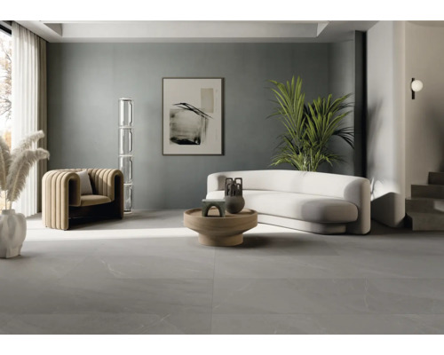 Heller Wohnraum mit Sofa, Sessel, Tisch und grauen Bodenfliesen