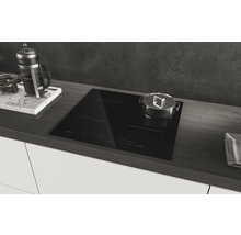 Schwarzes Induktionskochfeld in einer modernen Küche mit Topf und Kaffeebereiter
