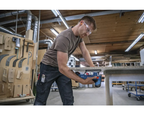 Ein Mann sägt mit einer Stichsäge ein Werkstück in einer Werkstatt.