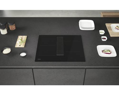 Schwarzes Haier Induktionskochfeld mit Dunstabzugshaube auf einer Küchenarbeitsplatte.