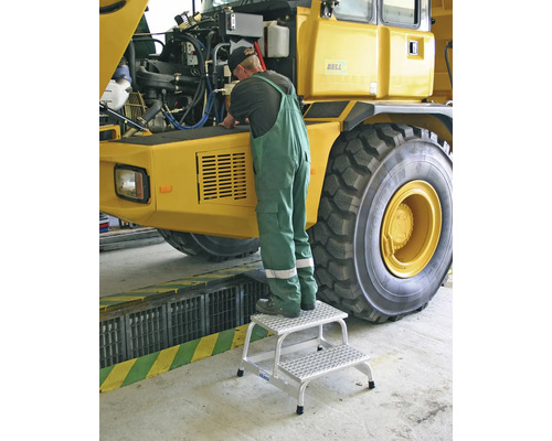 Eine Person benutzt einen zweistufigen Tritt, um an einem Fahrzeug zu arbeiten.