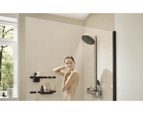 Eine Frau duscht in einem hellen Badezimmer mit Duschkopf und Ablageflächen.