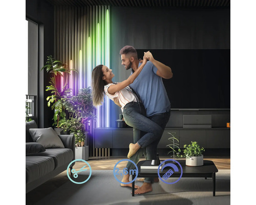 Tanzendes Paar im Wohnzimmer mit farbigen Lichtröhren als Dekoration