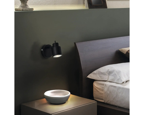 Schlafzimmer mit Nachttisch, Bett und schwarzer Wandleuchte
