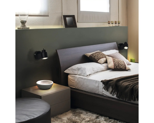 Schlafzimmer mit Doppelbett, Nachttisch, Wandlampen und dekorativen Elementen