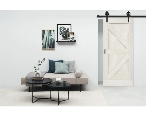 Wohnraum mit Schiebetür, Sofa, Couchtischen und Wanddekorationen für ein modernes Ambiente.