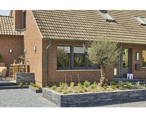 Außenansicht eines Hauses mit Ziegelmauerwerk, Fenstern, Tür und Gartengestaltung